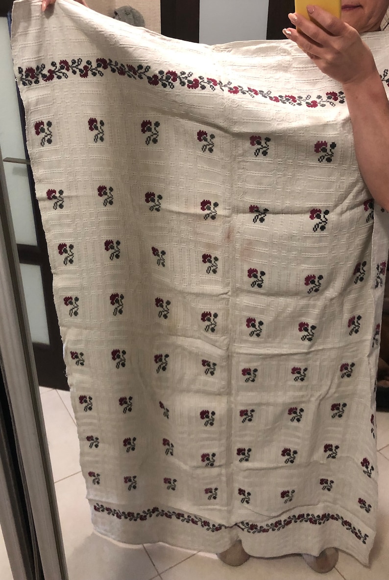 Peut inclure: Une nappe en lin blanche avec un motif r&eacute;p&eacute;t&eacute; de fleurs brod&eacute;es rouges et vertes. La nappe a une bordure de feuilles brod&eacute;es rouges et vertes.
