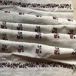 Peut inclure: Nappe en lin blanc avec un motif floral brod&eacute; rouge et noir. La nappe est pli&eacute;e en trois et a un tissage textur&eacute;.