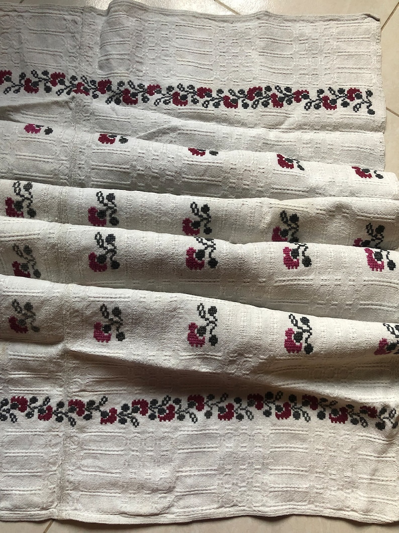 Peut inclure: Nappe en lin blanc avec un motif floral brod&eacute; rouge et noir. La nappe est pli&eacute;e en trois et a un tissage textur&eacute;.