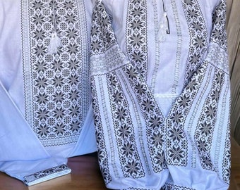 May include: A pair of white embroidered shirts with black floral patterns. The shirts have long sleeves and a traditional Ukrainian style.