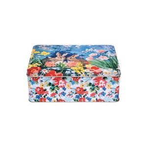May include: Rectangular tin box with a floral pattern and a lid featuring two rabbits in a garden scene. The box has a colorful floral design with red, blue, and yellow flowers. The overall aesthetic is vintage and charming.