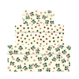 May include: Three nesting boxes with a cream background and a repeating pattern of green holly leaves, red berries, and gold stars.
