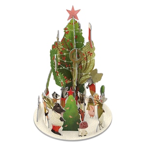 May include: A festive pop-up Christmas tree scene featuring woodland creatures. The green tree is adorned with red berries and a red star. The animals are dressed in winter clothing, creating a delightful holiday atmosphere.