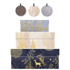 Può includere: Tre etichette regalo rotonde e tre scatole decorative. Le etichette sono marroni, beige e blu con un design strutturato. Le scatole sono blu, beige e blu navy con illustrazioni di foglie d'oro e cervi. Le scatole sono impilate.