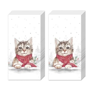 May include: Two stacks of rectangular paper napkins featuring a watercolour illustration of a brown tabby kitten wearing a red scarf with white snowflake patterns. The background shows a snowy winter scene with faint evergreen trees and holly berries.