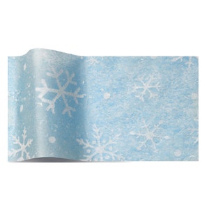 Pode incluir: Papel de seda azul com um padrão de floco de neve branco. O papel tem um aspecto texturizado e nevado.