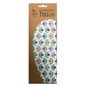 Può includere: Un pacchetto di carta marrone con il testo "CONTEMPORARY Tissue" e un logo per "deva" a forma di diamante. Il pacchetto contiene carta velina blu con un motivo geometrico colorato di cerchi e semicerchi.