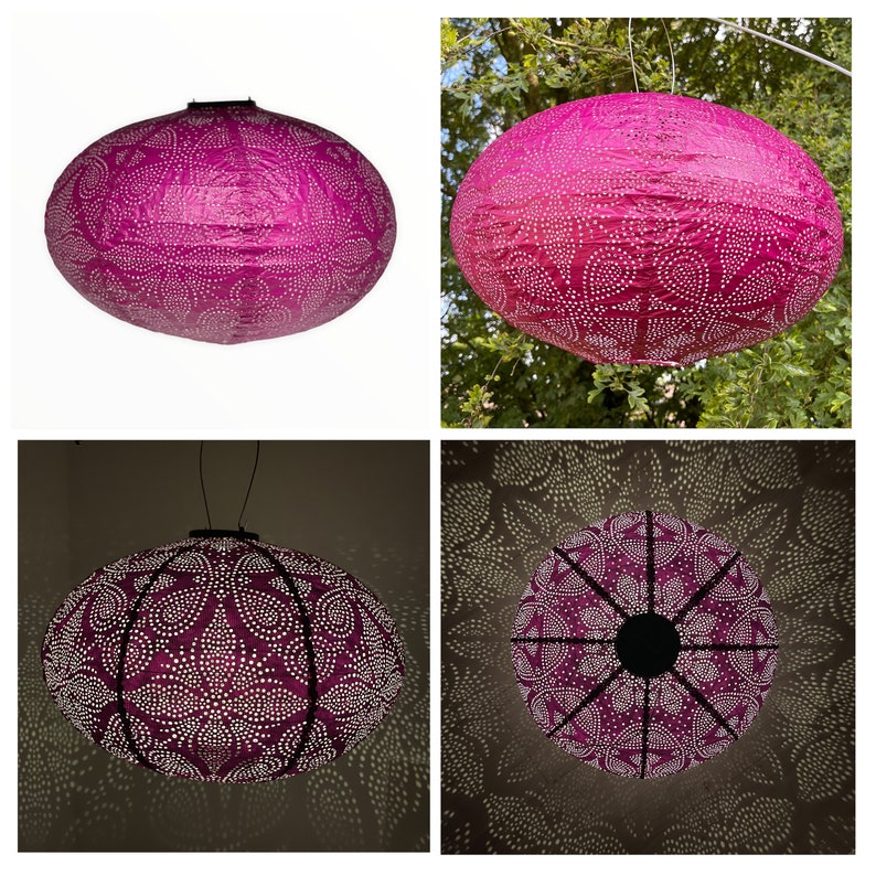 Puede incluir: Una linterna de papel rosa con un patr&oacute;n de lunares blancos y un marco de metal negro. La linterna est&aacute; colgada de una rama de &aacute;rbol y est&aacute; iluminada desde el interior, proyectando un brillo c&aacute;lido.