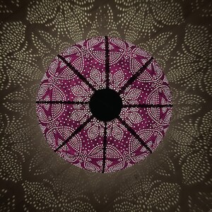 Puede incluir: Una pantalla de l&aacute;mpara de color morado con un patr&oacute;n geom&eacute;trico de puntos blancos y un centro negro. La pantalla proyecta una sombra en el techo.