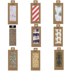 Könnte beinhalten: Neun Packungen Luxus-Seidenpapier mit verschiedenen weihnachtlichen Designs. Die Verpackungen aus braunem Karton tragen den Markennamen "glick". Designs umfassen rot-weiße Streifen, Weihnachtsbäume und Winterszenen.