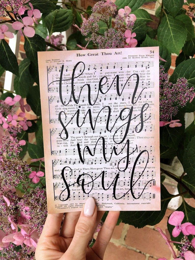 Puede incluir: Una p&aacute;gina de m&uacute;sica vintage con las palabras "How Great Thou Art!" y "Then sings my soul" escritas en caligraf&iacute;a negra sobre las notas musicales. La p&aacute;gina tiene un fondo de acuarela con tonos rosados y naranjas.