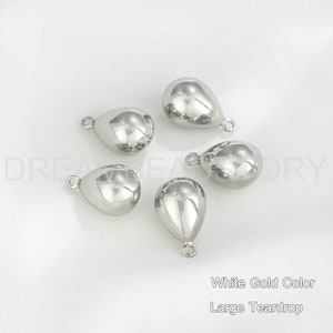 Peut inclure: Cinq breloques en forme de larme argent&eacute;es avec une boucle en haut. Couleur or blanc, grosse larme.