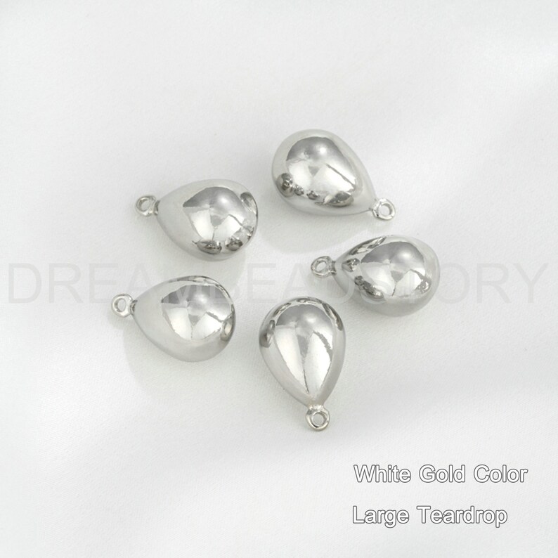 Peut inclure: Cinq breloques en forme de larme argent&eacute;es avec une boucle en haut. Couleur or blanc, grosse larme.