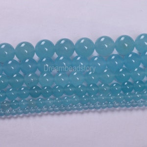 May include: Assortment of light blue round gemstone beads in various sizes. The beads are smooth and polished, with a translucent appearance.