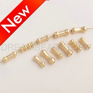 May include: Assortment of gold-toned metal beads in various shapes and sizes, including round, cylindrical, and teardrop shapes. The beads are strung on a wire and are ready for jewelry making.