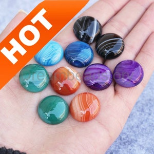 Puede incluir: Surtido de diez cabujones de ágata en varios colores, incluyendo azul, verde, rojo, morado y negro. Los cabujones son redondos y tienen una superficie lisa y pulida.