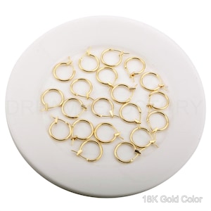 May include: A collection of 18K gold-colored hoop earrings. The earrings are small and delicate, and they are perfect for everyday wear.