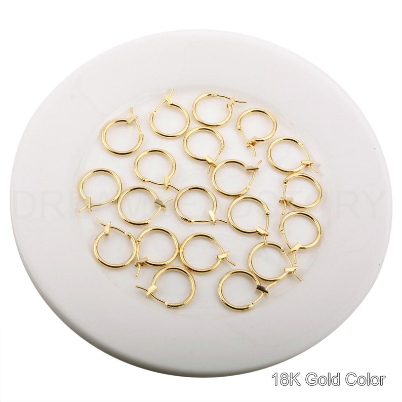 May include: A collection of 18K gold-colored hoop earrings. The earrings are small and delicate, and they are perfect for everyday wear.