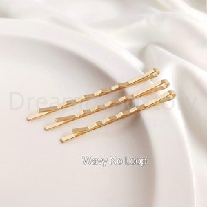 May include: Three gold wavy hair clips without loops. The clips are on a white surface.