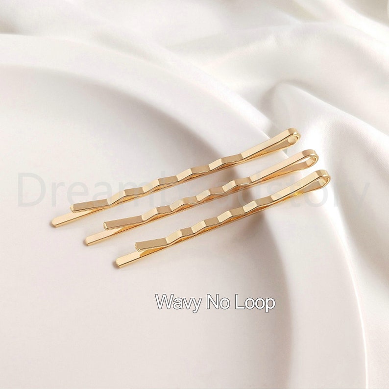 May include: Three gold wavy hair clips without loops. The clips are on a white surface.