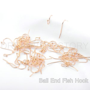 May include: A large pile of gold-toned ball end fish hooks. The hooks are all the same size and shape, and they are arranged in a random pattern. The hooks are a popular choice for jewelry making and other crafts.