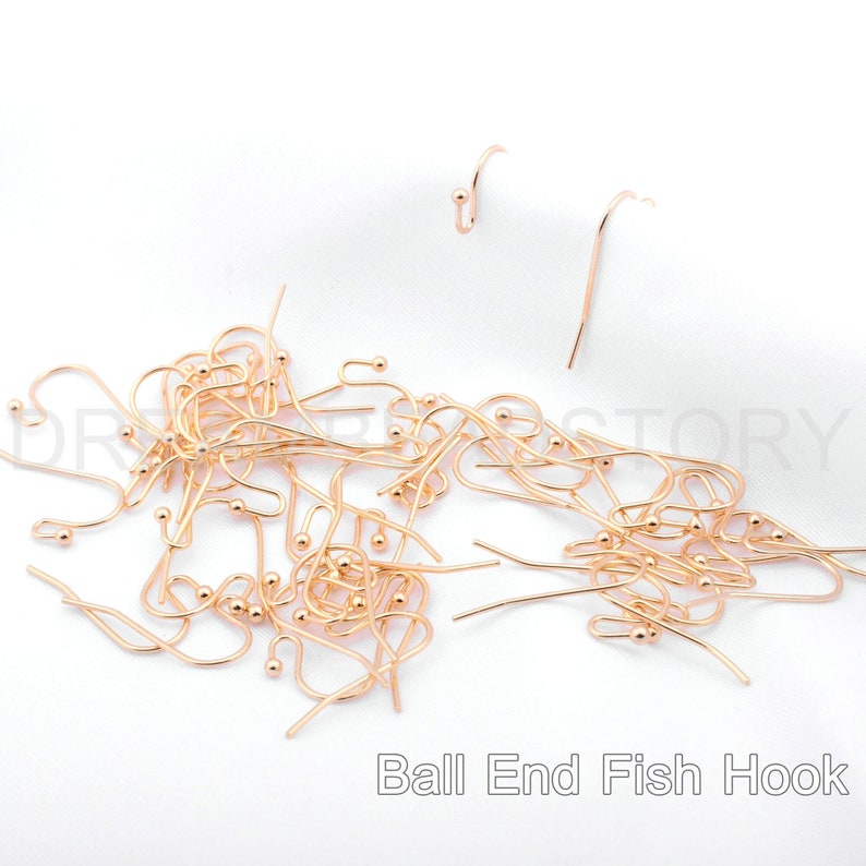 May include: A large pile of gold-toned ball end fish hooks. The hooks are all the same size and shape, and they are arranged in a random pattern. The hooks are a popular choice for jewelry making and other crafts.
