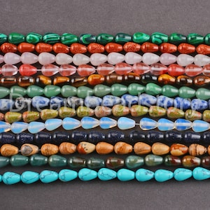 Op de afbeelding: Assortiment van edelsteen kralen in verschillende kleuren en vormen, waaronder turquoise, groen, bruin, blauw en roze. De kralen zijn gerangschikt in rijen, waarbij elke rij een ander type edelsteen laat zien.