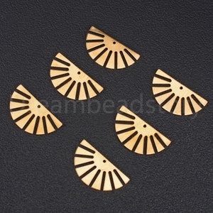 May include: Six gold-colored metal half-circle shapes with a sunburst design. Each shape has a small hole in the center.