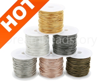May include: Six spools of metallic cord in different colors: gold, silver, black, rose gold, and bronze. The cord is wound around white spools.