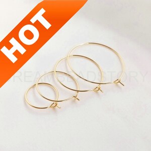 May include: Three gold hoop earrings of different sizes. The hoops are made of thin wire and have a simple, elegant design.
