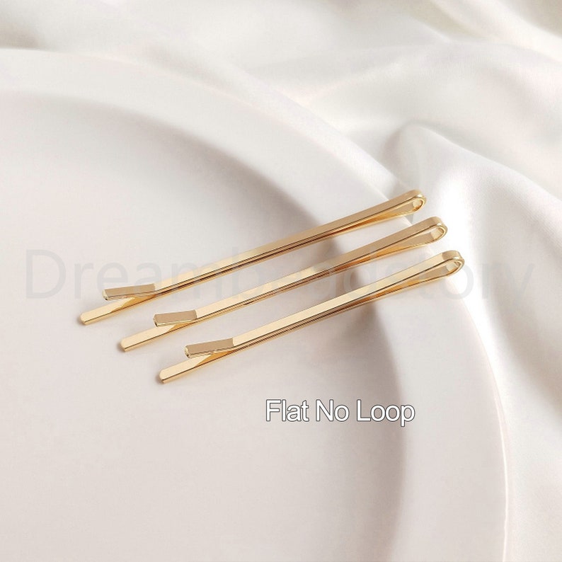May include: Three gold hair clips with a flat, no-loop design.  The clips are arranged in a row on a white surface.  Flat No Loop.