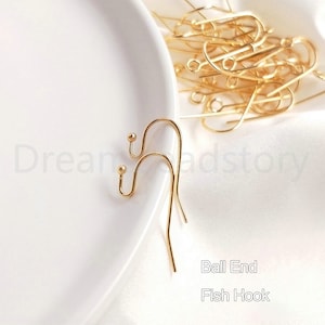May include: Two gold ball end fish hook earring findings. The hooks are made of metal and have a smooth, shiny finish.