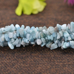 May include: A strand of light blue aquamarine chip beads. The beads are irregular in shape and have a smooth, polished finish.