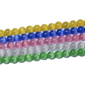 May include: A strand of round, smooth, cat's eye beads in five colors: yellow, blue, pink, white, and green.