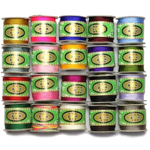May include: Twenty spools of colourful embroidery floss, each with a green label that reads "金剛" in Chinese characters. The spools are arranged in four rows of five.