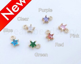 May include: Assortment of star-shaped charms with different colored crystals. The charms are gold-toned and have a loop for attaching to jewelry. Colors include clear, blue, green, red, pink, and purple.