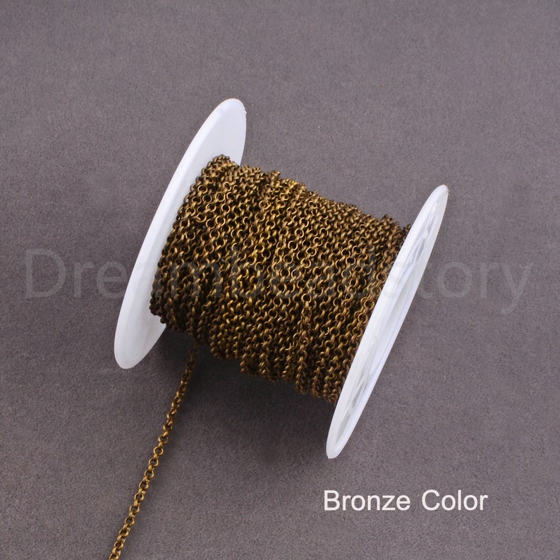 Peut inclure: Une bobine de cha&icirc;ne de couleur bronze, enroul&eacute;e autour d'une bobine en plastique blanc. La cha&icirc;ne est fine et d&eacute;licate.