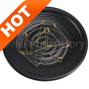 May include: A group of ten gold triangle shaped wire hoops, with a jump ring at each point, are displayed on a black plate.