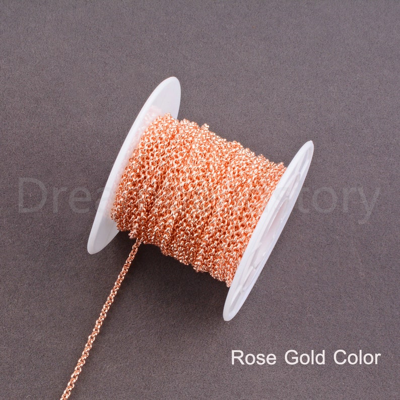 Peut inclure: Une bobine de cha&icirc;ne de couleur or rose, enroul&eacute;e autour d'une bobine en plastique blanc. La cha&icirc;ne est de style &agrave; maillons fins et d&eacute;licats.