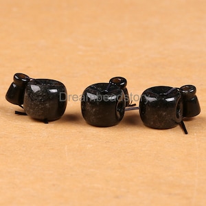 Puede incluir: Tres cuentas de piedra preciosa negra con un agujero en el centro. Las cuentas son redondas y tienen una superficie lisa y pulida.