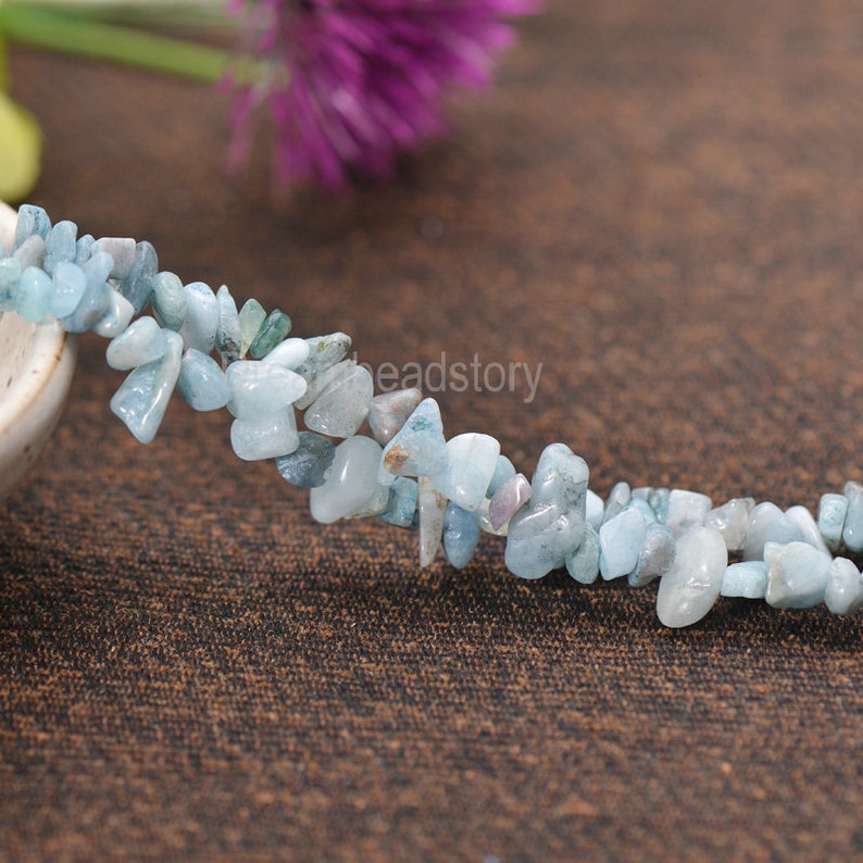 May include: A strand of light blue aquamarine chip beads. The beads are irregular in shape and have a natural, tumbled finish.