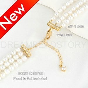Pode incluir: Extensor de colar dourado com três barras e uma corrente pequena com um cristal transparente na ponta. O extensor é para um colar de pérolas e tem uma etiqueta de tamanho pequeno. O texto "with 3 Bars" e "Small Size" é visível na imagem. O texto "Usage Example Pearl is Not Included" também é visível na imagem.