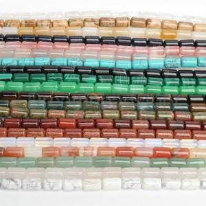 Puede incluir: Surtido de cuentas de piedras preciosas de colores en forma rectangular. Las cuentas están dispuestas en filas, mostrando una variedad de colores y patrones.