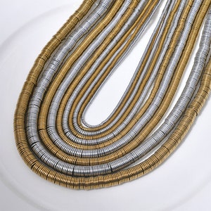 Pu&ograve; includere: Una collana multifilo realizzata con anelli di metallo dorato e argentato. La collana &egrave; composta da pi&ugrave; strati di anelli, creando un effetto a strati.