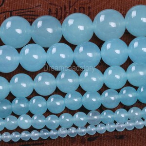 May include: A collection of smooth, round, light blue beads of varying sizes. The beads are made of natural stone and have a polished finish.
