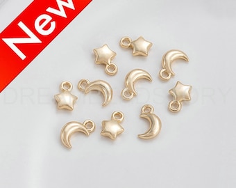 May include: A collection of gold-toned metal charms featuring crescent moons and stars. The charms have a loop at the top for attaching to jewelry or other crafts.