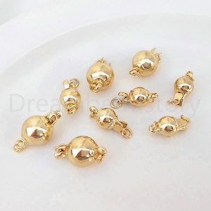 May include: Eight gold-toned metal clasps for necklaces or bracelets. Each clasp is a round ball with a hinged opening.