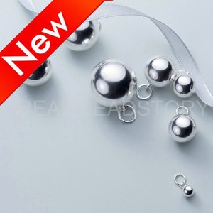 Op de afbeelding: Een set zilverkleurige metalen balbedels met een lus om aan sieraden te bevestigen. De bedels zijn in verschillende maten verkrijgbaar, waarbij de grootste ongeveer 2,5 cm in diameter is.