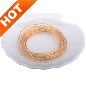 Pode incluir: Uma bobina de fio dourado em um prato branco em forma de concha.