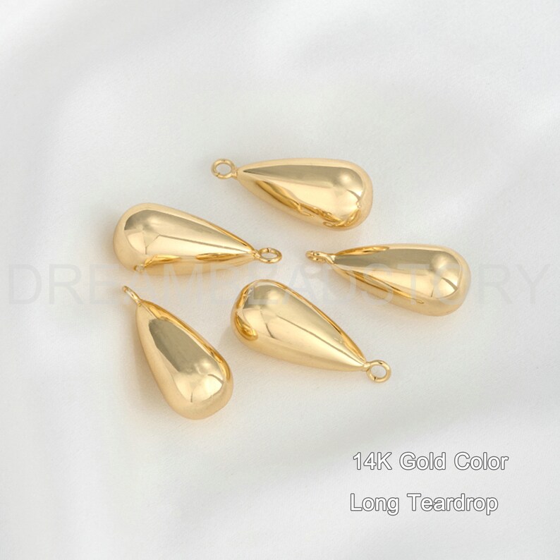 Peut inclure: Cinq breloques en forme de larme longue de couleur or avec une boucle en haut. 14K Gold Color Long Teardrop.